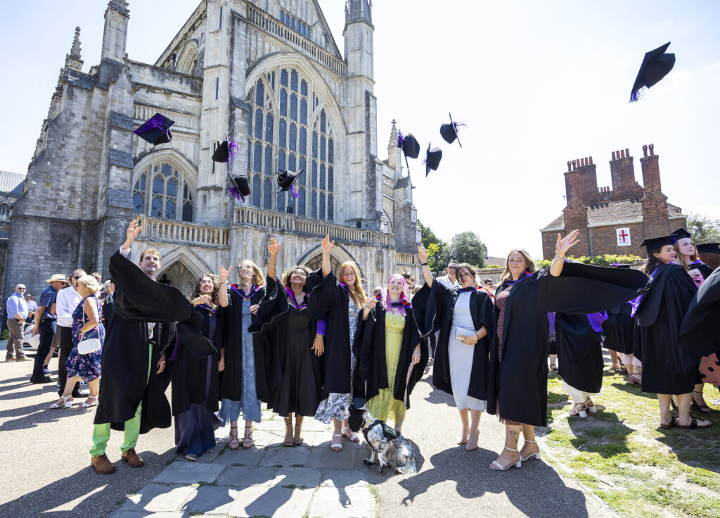 University Centre Sparsholt students celebrate their graduation in front of the Winchester Cathedral by throwing their mortarboards in the air