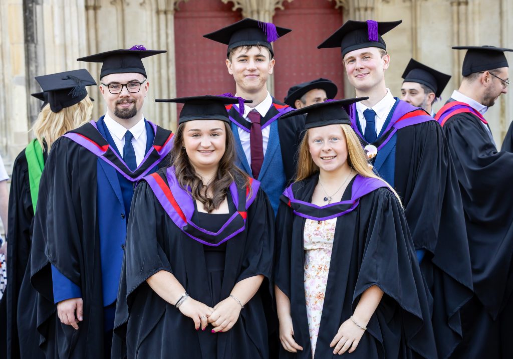 Group of University Centre Sparsholt graduates in traditional academic robes posing outside Winchester Cathedral at University Centre Sparsholt graduation