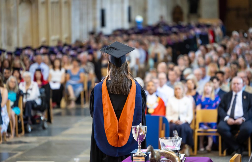 CEO of Sparsholt College Group in academic gown and cap standing at podium during University Centre Sparsholt graduation ceremony inside Winchester Cathedral